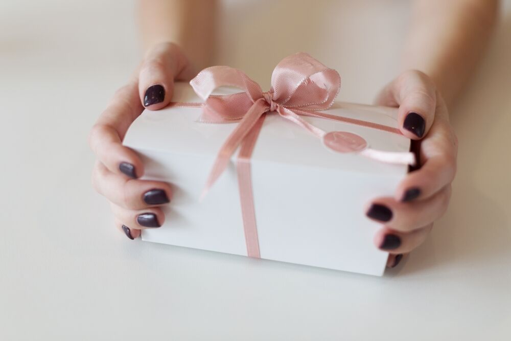 Geschenk wird mit einer rosé Schleife gebunden