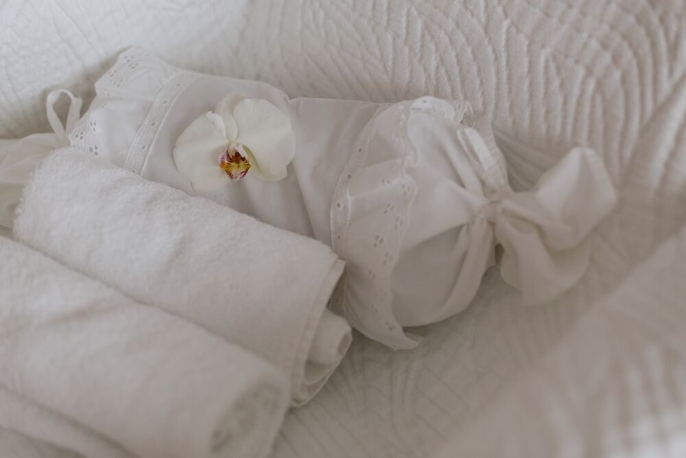 Gerollte Frotteetücher mit weißer Orchidee auf heller Wäsche
